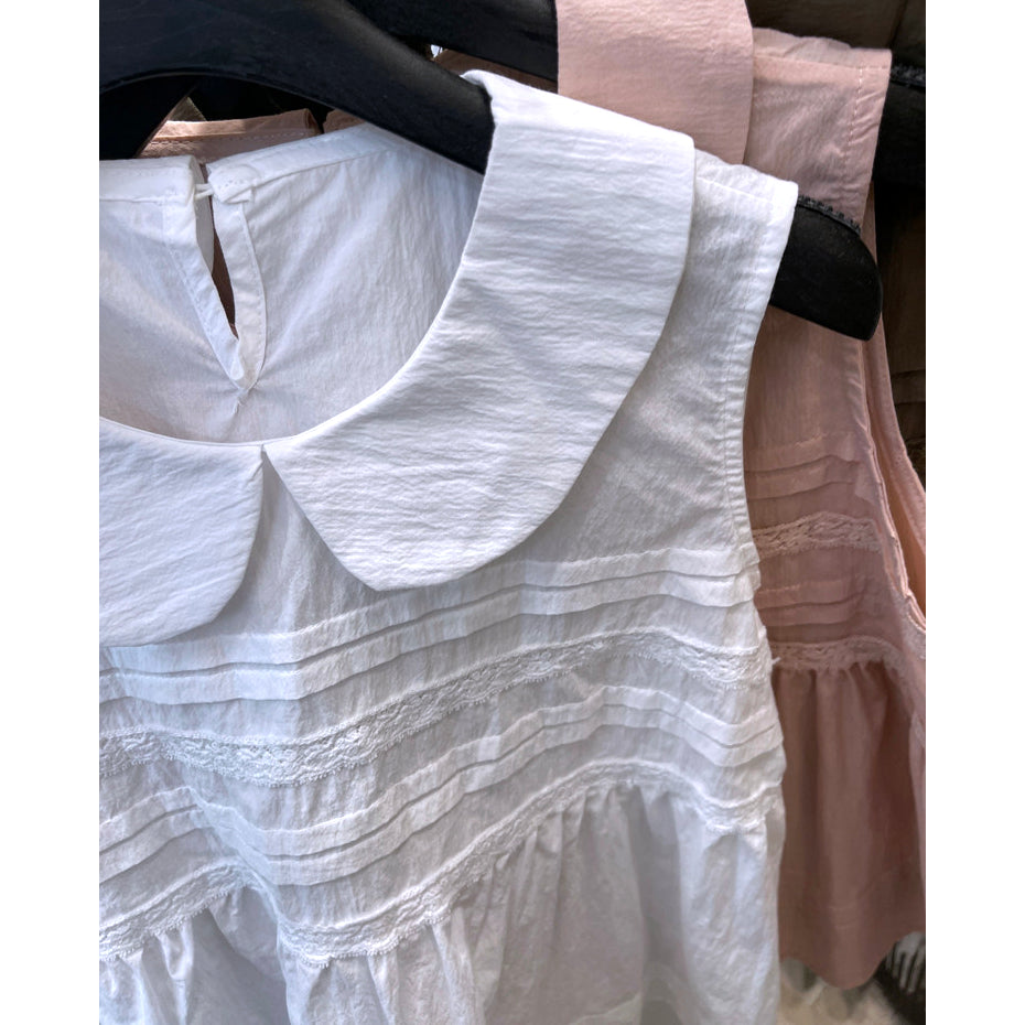 Close-up of Peter Pan collar and pintuck pleat details on white sleeveless babydoll top